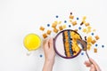 Breakfast, female hands holding a spoon over a bowl with homemade yogurt and cornflakes, and fresh blueberries, a glass of orange