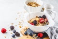 Breakfast food background. Granola with hemp seeds, maca powder, peanut butter and berries on white table