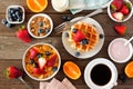 Breakfast food table scene. Fruits, cereal, waffles, yogurt and coffee. Top view over wood. Royalty Free Stock Photo