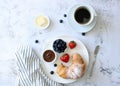 Breakfast in French style: croissant, butter, coffee with milk, berries on a light background, top view. Royalty Free Stock Photo