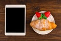 Breakfast with fresh croissants, fresh strawberry on a rustic wooden background, top view. tablet pc.