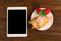 Breakfast with fresh croissants, fresh strawberry on a rustic wooden background, top view. tablet pc.