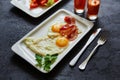 Breakfast from fried egg, bacon, vegetable salad and carrot juice. On a dark stone background Royalty Free Stock Photo