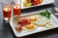 Breakfast from fried egg, bacon, vegetable salad and carrot juice. On a dark stone background Royalty Free Stock Photo