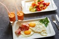 Breakfast from fried egg, bacon, vegetable salad and carrot juice. On a dark stone background Royalty Free Stock Photo