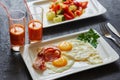 Breakfast from fried egg, bacon, vegetable salad and carrot juice. On a dark stone background Royalty Free Stock Photo