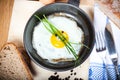 Breakfast with fried egg in old frying pan on wooden plate