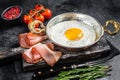 Breakfast with fried egg in a skilet with tomatoes and bacon. Black background. Top view Royalty Free Stock Photo