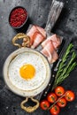 Breakfast with fried egg in a skilet with tomatoes and bacon. Black background. Top view Royalty Free Stock Photo