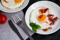 Breakfast. Fried eggs with bacon decorated with basil leaves. Nearby is a cup of coffee with toast. Royalty Free Stock Photo