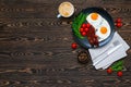 Breakfast with fried eggs, crispy bacon, fresh cherry tomatoes, rocket salad and cup of coffee served on the wooden table with kni Royalty Free Stock Photo