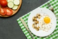 Breakfast with fried eggs, mushrooms and vegetables in a white plate on dark background, top view Royalty Free Stock Photo