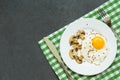 Breakfast with fried eggs, mushrooms and vegetables in a white plate on dark background, top view Royalty Free Stock Photo