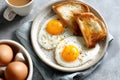 Breakfast with fried eggs and toasted bread on a plate next to a cup of coffee and a bowl of eggs Royalty Free Stock Photo
