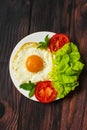 Breakfast with fried eggs and vegetables and fried tomato pieces on wood background. Royalty Free Stock Photo