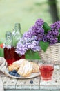 Breakfast in the garden: eclairs, cup of coffee, coffee pot, lilac flowers in a basket Royalty Free Stock Photo