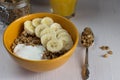 Breakfast of granola with banana and yogurt in a bowl on a table on a white wooden background Royalty Free Stock Photo