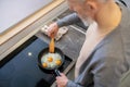 A gray-haired man cooking omlette in the kitchen