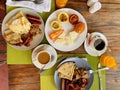 Breakfast in the hotel restaurant on the table with scrambled eggs, bacon, pancakes, sausages, mushrooms, coffee, juice and fruit Royalty Free Stock Photo