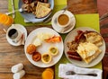 Breakfast in the hotel restaurant on the table with scrambled eggs, bacon, pancakes, sausages, mushrooms, coffee, juice and fruit Royalty Free Stock Photo