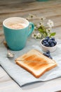 Breakfast idea. Cup with coffee with blueberries, flowers and toast on linen napkin