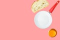 Breakfast ingredients slice of white bread cracked raw egg with bright yellow yolk frying pan on pink background