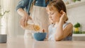 Breakfast in the Kitchen: Young Beautiful Mother Pours Cereal into Bowl, Adorable Little Daughter Royalty Free Stock Photo