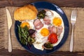 Breakfast or lunch with fried eggs, bread toast, arugula leaves, tomato, pork ham or bacon and broccoli on a dark blue plate Royalty Free Stock Photo