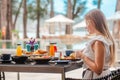 Breakfast in luxury hotel. Woman sitting in outdoor cafe, eating healthy food in hotel near swimming pool, sea and sun Royalty Free Stock Photo