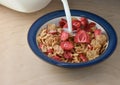 Breakfast meal pouring milk into a bowl of flakes with freeze dr