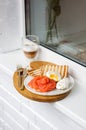 Breakfast menu: toasted bread, smoked salmon, poached eggs and cup of coffee on white windowsill