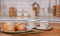 Breakfast. Morning coffee with croissants. Two white cups and two croissants on white plates on a tray against the background of a