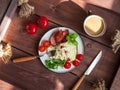 Breakfast from an omelet with fried sausage and fresh tomatoes, and arugula and basil, coffee with milk in a ceramic mug, cutlery Royalty Free Stock Photo