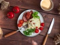 Breakfast from an omelet with fried sausage and fresh tomatoes, and arugula and basil, coffee with milk in a ceramic mug, cutlery Royalty Free Stock Photo