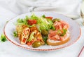 Breakfast. Omelette roll with tomatoes and sandwich with salmon on white plate