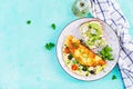 Omelette with tomatoes, black olives and sandwich with avocado on white plate.