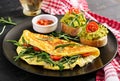 Breakfast. Omelette with tomatoes, cheese, green arugula and toasts with avocado cream
