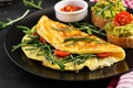 Breakfast. Omelette with tomatoes, cheese, green arugula and toasts with avocado cream