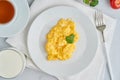 Breakfast with pan-fried scrambled eggs, cup of tea, tomatoes on white background. Omelette, top view Royalty Free Stock Photo