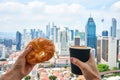 Breakfast in a picturesque place. Man holds in his hand a cup of coffee and a croissant on the balcony of a skyscraper with a view Royalty Free Stock Photo