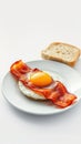 Breakfast plate with crispy bacon, sunny-side up egg, and a slice of bread served on a white plate Royalty Free Stock Photo
