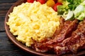 Breakfast plate . Scrambled eggs , bacon , cherry tomatoes and salad Royalty Free Stock Photo