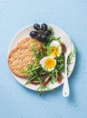 Breakfast plate - whole wheat cracker, arugula, cherry tomatoes, boiled egg salad on blue background