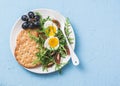 Breakfast plate - whole wheat cracker, arugula, cherry tomatoes, boiled egg salad on blue background