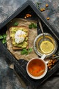 Breakfast poached egg, avocado guacamole sandwich, tea, lemon on a wooden tray. Rustic background. Tea with sea buckthorn. Top vie