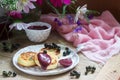 Breakfast of quark pancakes, black currant custard, currants and a bouquet of wild flowers on a wooden background