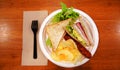 Breakfast at the restaurant. Sandwich, sausage and potato chips in the white paper plate.
