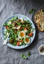 Breakfast salad - rocket, cherry tomatoes, mozzarella and boiled egg with olive oil, mustard, lemon dressing on a grey background Royalty Free Stock Photo