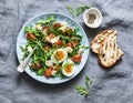 Breakfast salad - rocket, cherry tomatoes, mozzarella and boiled egg with olive oil, mustard, lemon dressing on a grey background Royalty Free Stock Photo