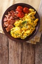 Breakfast is scrambled eggs with chives, fried bacon closeup. vertical top view